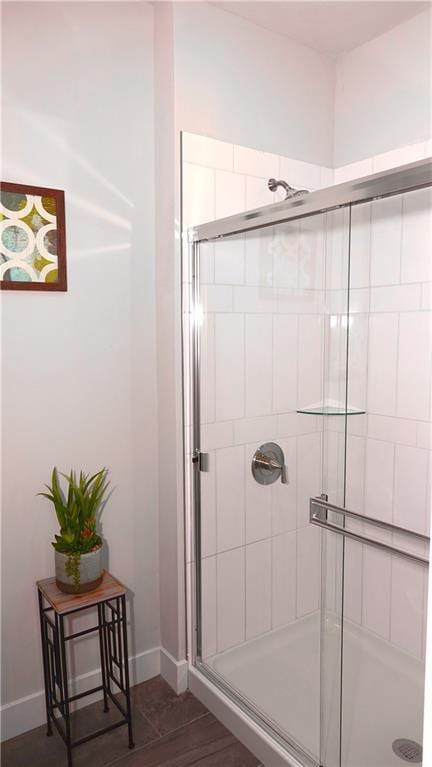 full bath featuring baseboards, tiled shower, and wood finished floors