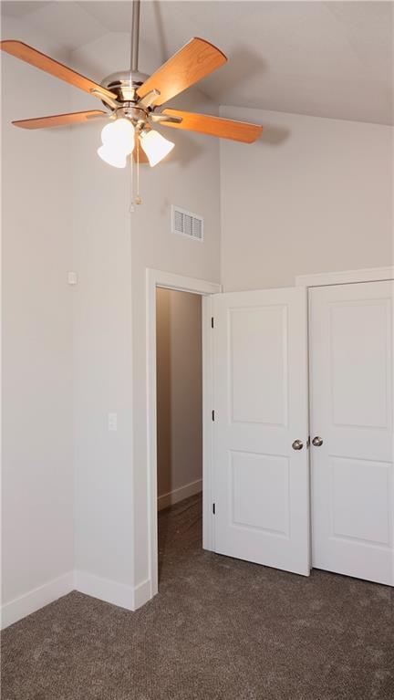 unfurnished bedroom featuring visible vents, dark carpet, ceiling fan, and baseboards