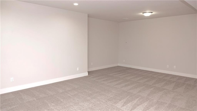 empty room featuring recessed lighting, light carpet, and baseboards