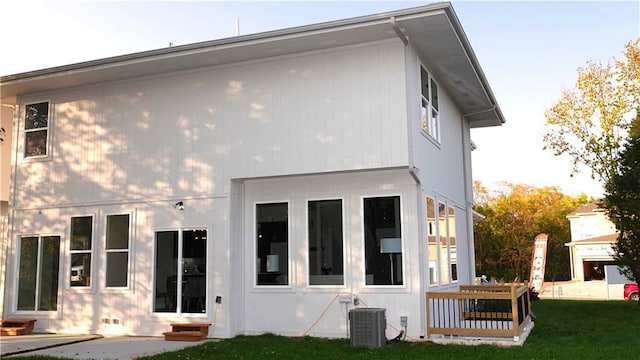 rear view of house with entry steps, a yard, and cooling unit