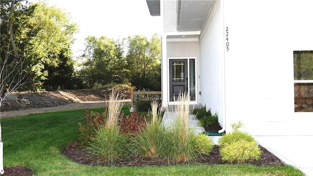 property entrance featuring a lawn and stucco siding