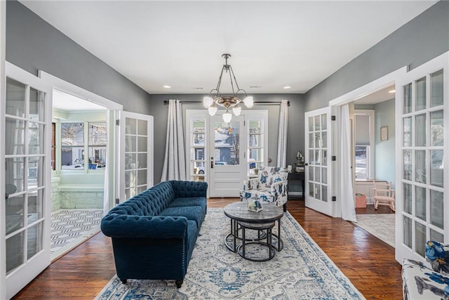 living area featuring french doors, an inviting chandelier, and wood finished floors