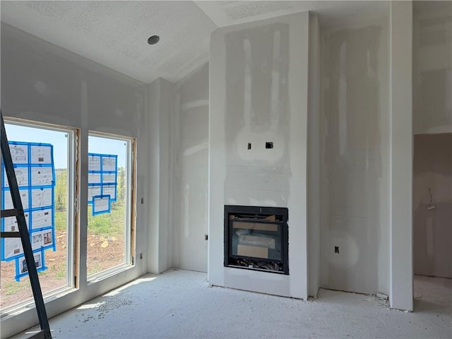 17388 S Kaw St, Olathe, KS 66062 - unfurnished living room featuring a glass covered fireplace, vaulted ceiling, and a textured ceiling