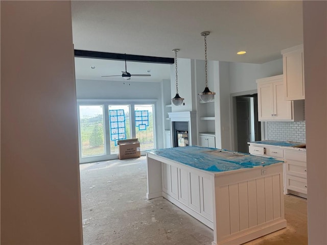 17388 S Kaw St, Olathe, KS 66062 - kitchen featuring white cabinetry, a fireplace, ceiling fan, tasteful backsplash, and a kitchen island