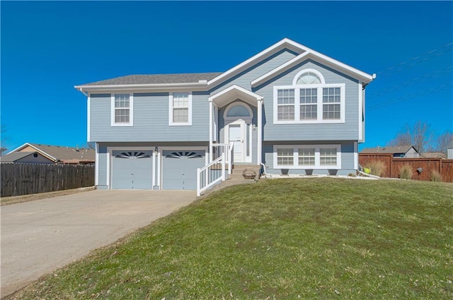 bi-level home with a garage, fence, a front lawn, and concrete driveway