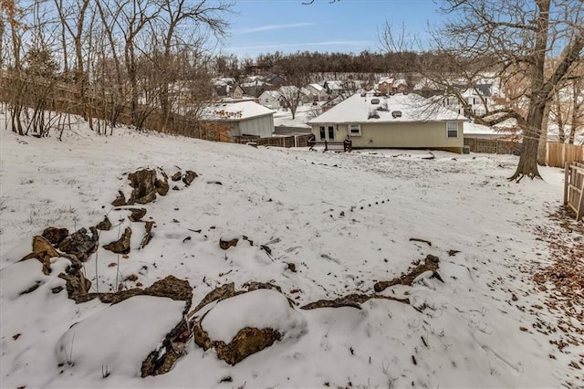 yard layered in snow featuring a garage and fence