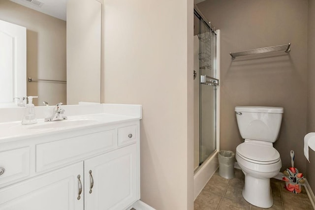 bathroom featuring a shower with door, toilet, vanity, baseboards, and tile patterned floors