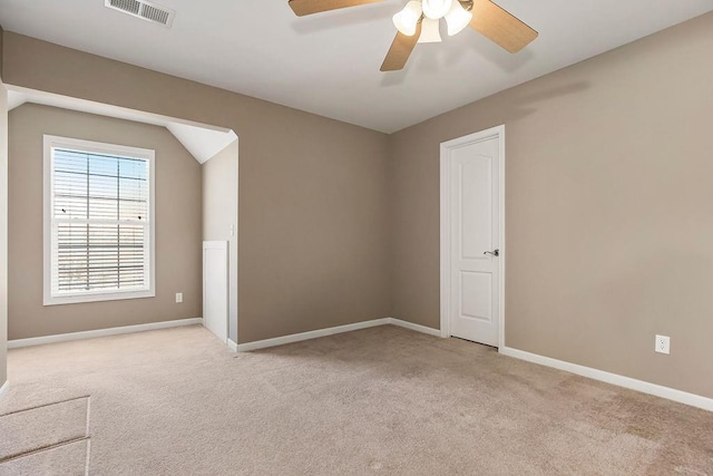 empty room with light carpet, baseboards, visible vents, lofted ceiling, and ceiling fan