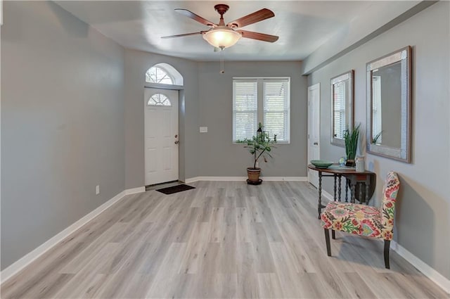 foyer featuring a ceiling fan, baseboards, and light wood finished floors