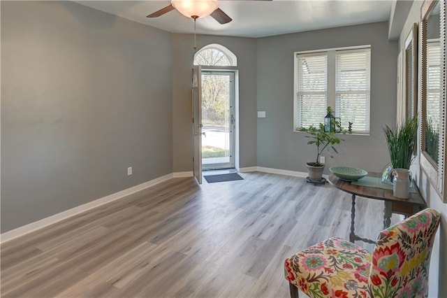 foyer entrance with a ceiling fan, baseboards, and wood finished floors