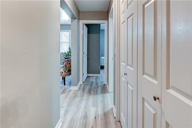 corridor featuring baseboards and light wood-style floors