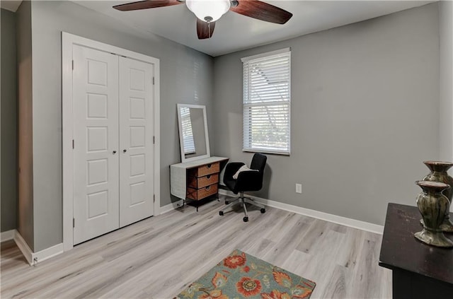 office area with baseboards, light wood-style floors, and a ceiling fan