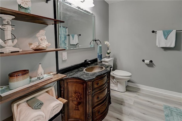 half bath with vanity, toilet, wood finished floors, and baseboards