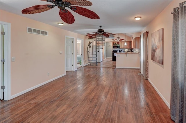 unfurnished living room featuring visible vents, stairs, baseboards, and hardwood / wood-style floors