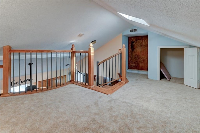 additional living space with lofted ceiling with skylight, visible vents, a textured ceiling, and carpet floors