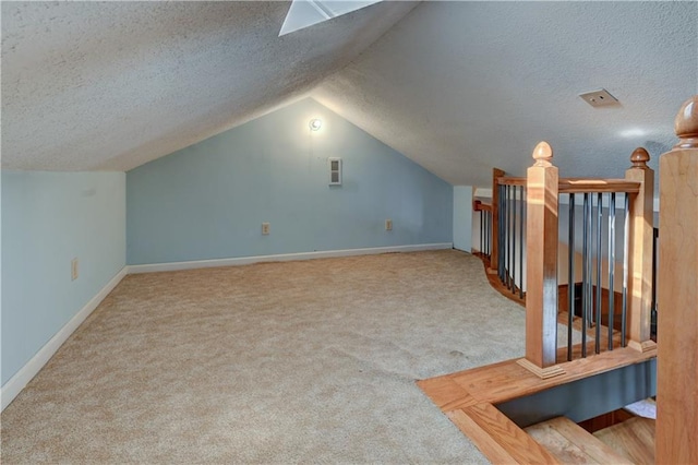 additional living space featuring vaulted ceiling, carpet, baseboards, and a textured ceiling