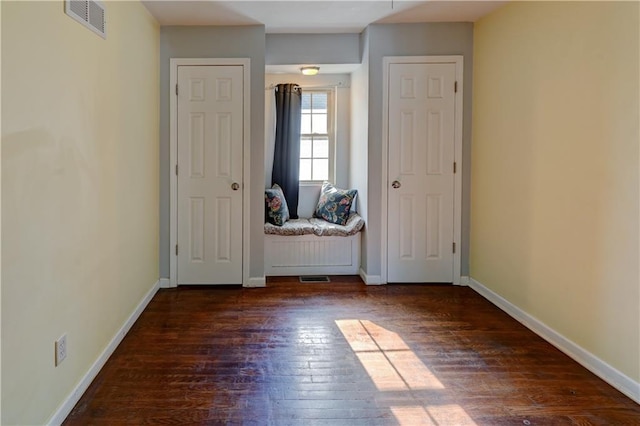 unfurnished bedroom featuring visible vents, baseboards, and dark wood-style flooring