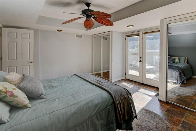 bedroom featuring baseboards, visible vents, stone finish flooring, a raised ceiling, and access to outside