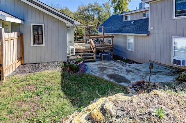 view of side of home with a patio, central AC unit, a deck, and a shingled roof