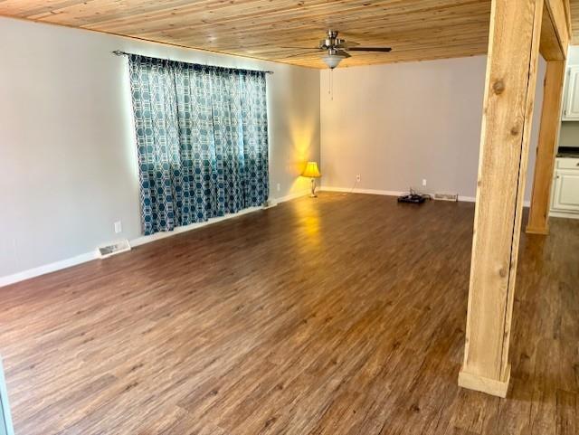 empty room featuring visible vents, a ceiling fan, wood ceiling, wood finished floors, and baseboards