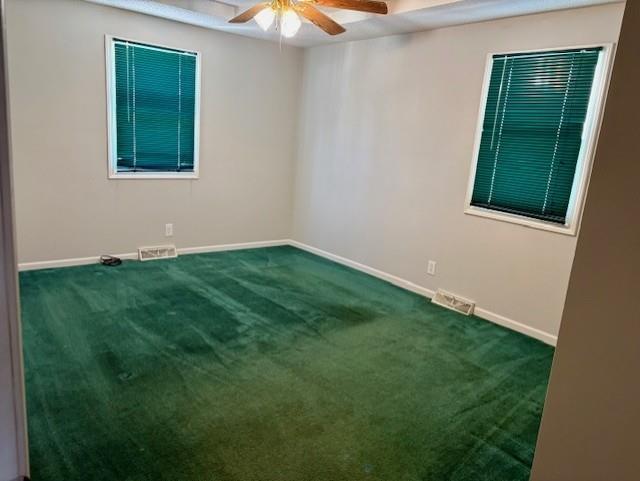 carpeted spare room with a ceiling fan, visible vents, and baseboards