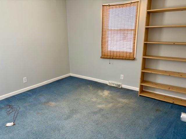 spare room with visible vents, baseboards, and dark colored carpet