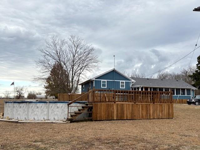 back of house featuring stairs, a deck, and an outdoor pool