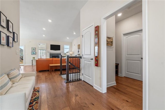 interior space featuring lofted ceiling, hardwood / wood-style flooring, recessed lighting, a fireplace, and baseboards