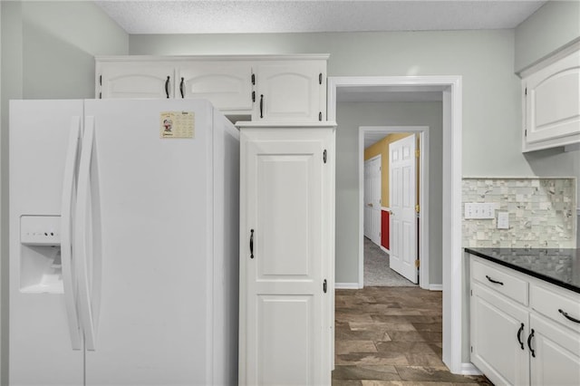 kitchen with dark countertops, decorative backsplash, dark wood-type flooring, white cabinetry, and white fridge with ice dispenser