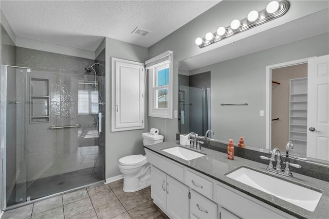 bathroom featuring double vanity, a shower stall, visible vents, and a sink