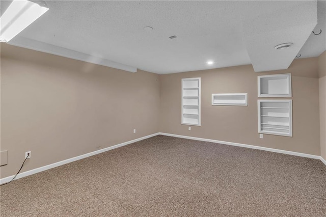 spare room with built in shelves, carpet floors, baseboards, and a textured ceiling