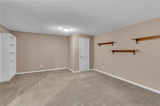 spare room featuring baseboards, a textured ceiling, and light colored carpet