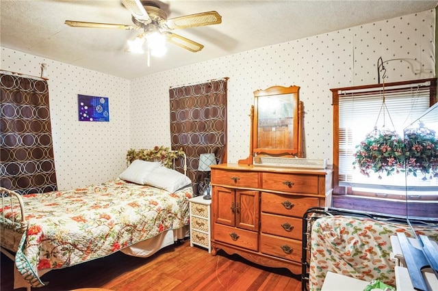 bedroom with wallpapered walls, a ceiling fan, vaulted ceiling, and wood finished floors