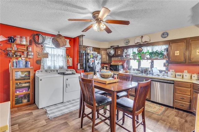 kitchen with light wood finished floors, brown cabinetry, washing machine and clothes dryer, light countertops, and black appliances