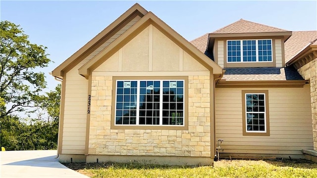 view of property exterior with stone siding and roof with shingles