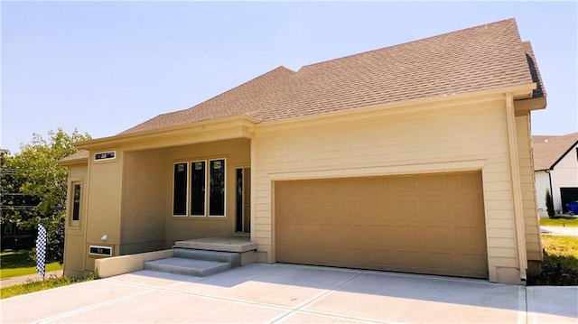 view of front of property with an attached garage, concrete driveway, and roof with shingles