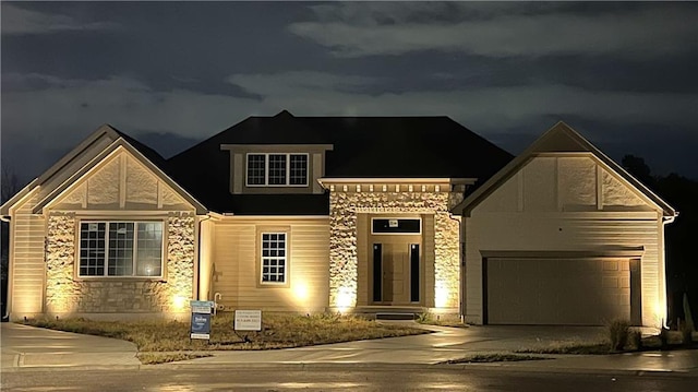 view of front of house with driveway, stone siding, and a garage