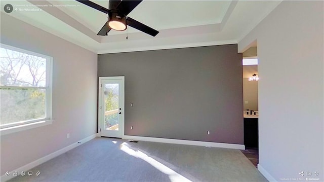 carpeted spare room with ceiling fan, baseboards, and a raised ceiling