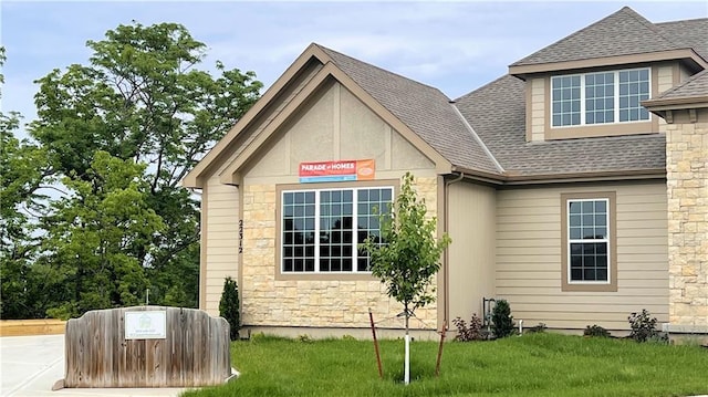 22312 W 76th St, Shawnee, KS 66227 - view of side of property with stone siding, a shingled roof, and a lawn
