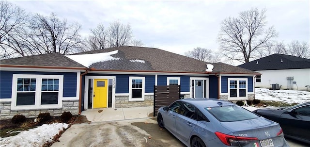 view of front facade featuring stone siding and a shingled roof