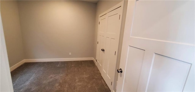 interior space featuring dark colored carpet and baseboards