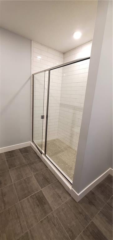 bathroom with a shower stall, baseboards, and tile patterned floors