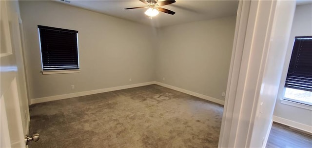 unfurnished room with ceiling fan, dark colored carpet, and baseboards