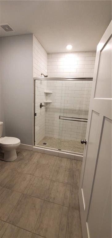 full bathroom featuring toilet, a stall shower, and visible vents