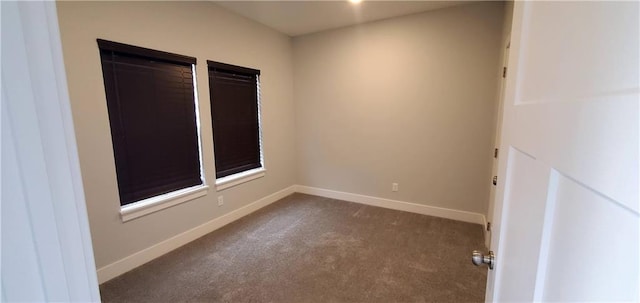 empty room with dark carpet and baseboards