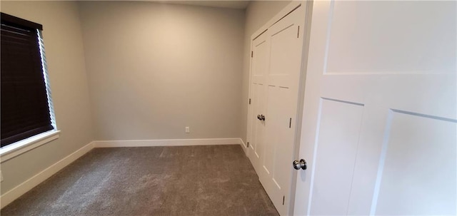 empty room with dark colored carpet and baseboards