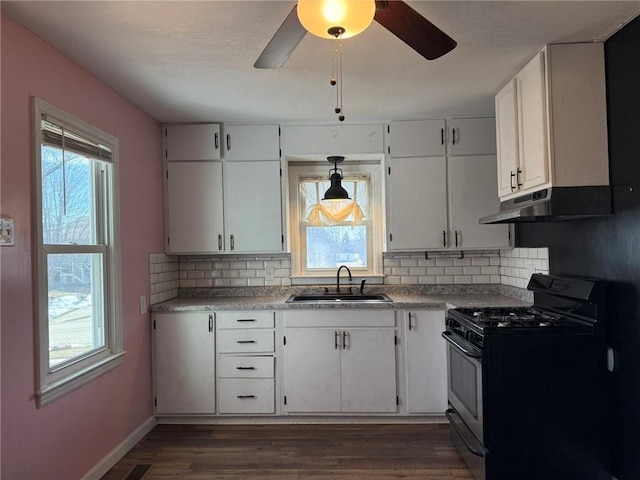 kitchen featuring dark wood-style flooring, a healthy amount of sunlight, a sink, gas range, and under cabinet range hood