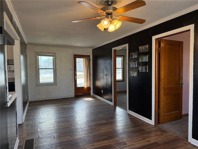 interior space with dark wood-style floors, visible vents, ornamental molding, a ceiling fan, and baseboards