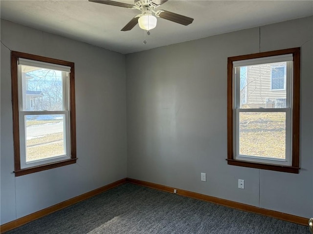 carpeted spare room with plenty of natural light, a ceiling fan, and baseboards