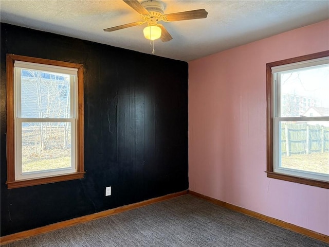 carpeted empty room with ceiling fan, baseboards, and a textured ceiling